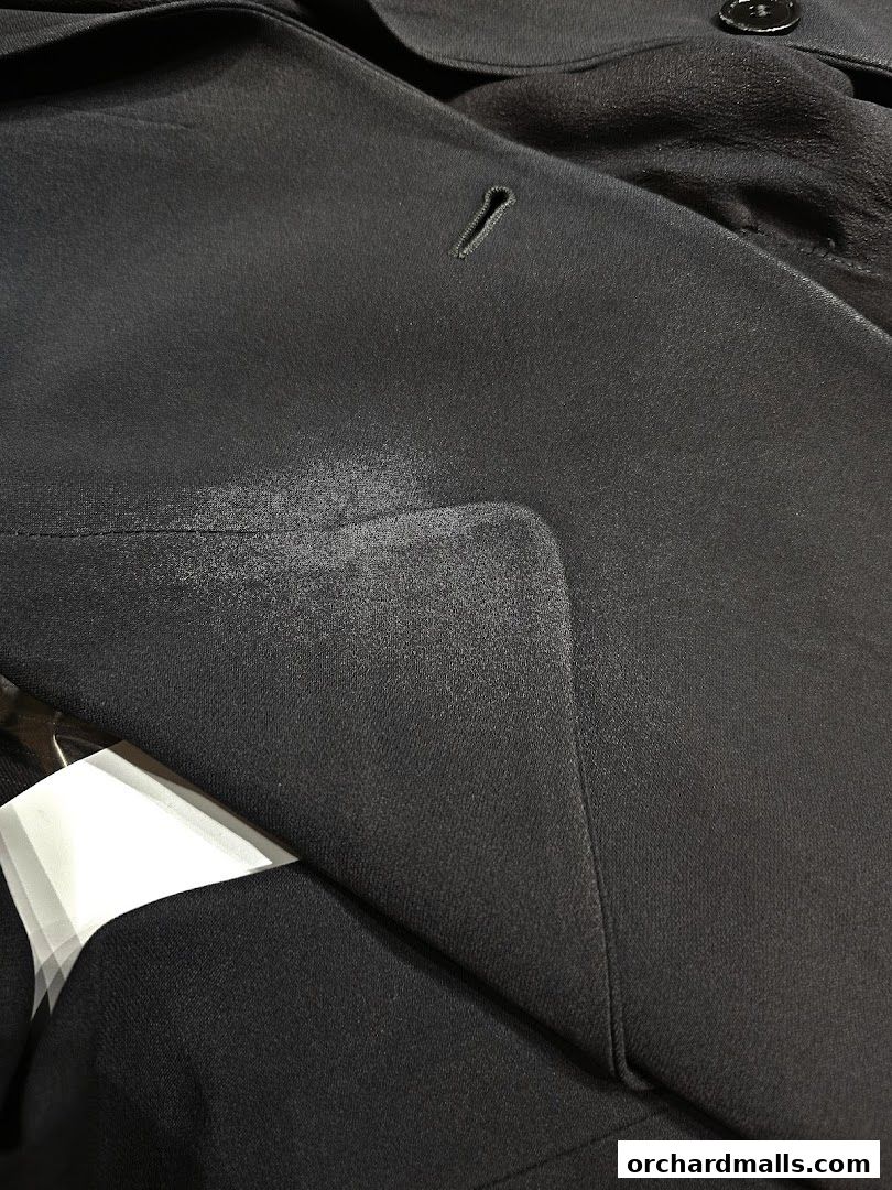 Close-up of a dark fabric with a stain on a lapel, possibly a suit jacket.