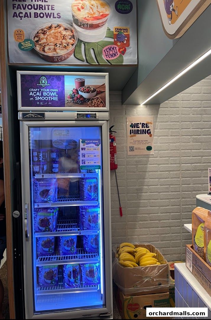 Project Acai shop interior with a freezer full of acai products and a display of bananas.