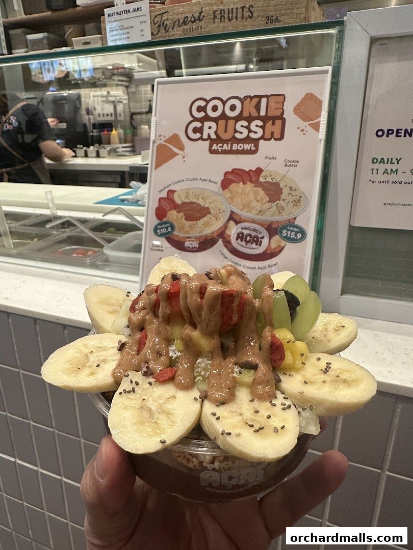 A hand holds a delicious acai bowl topped with fruits and nut butter.