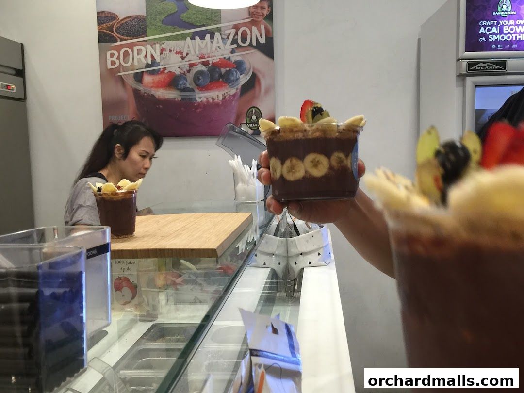 A person holds an acai bowl with fruit toppings at Project Acai.