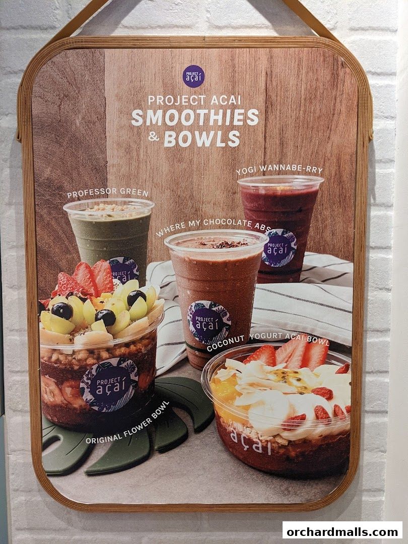 A sign showcasing Project Acai's smoothies and bowls with vibrant fruit toppings.