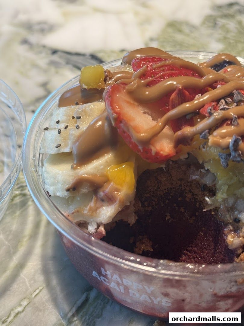 A close-up of a delicious acai bowl topped with strawberries, bananas, and a drizzle of peanut butter.