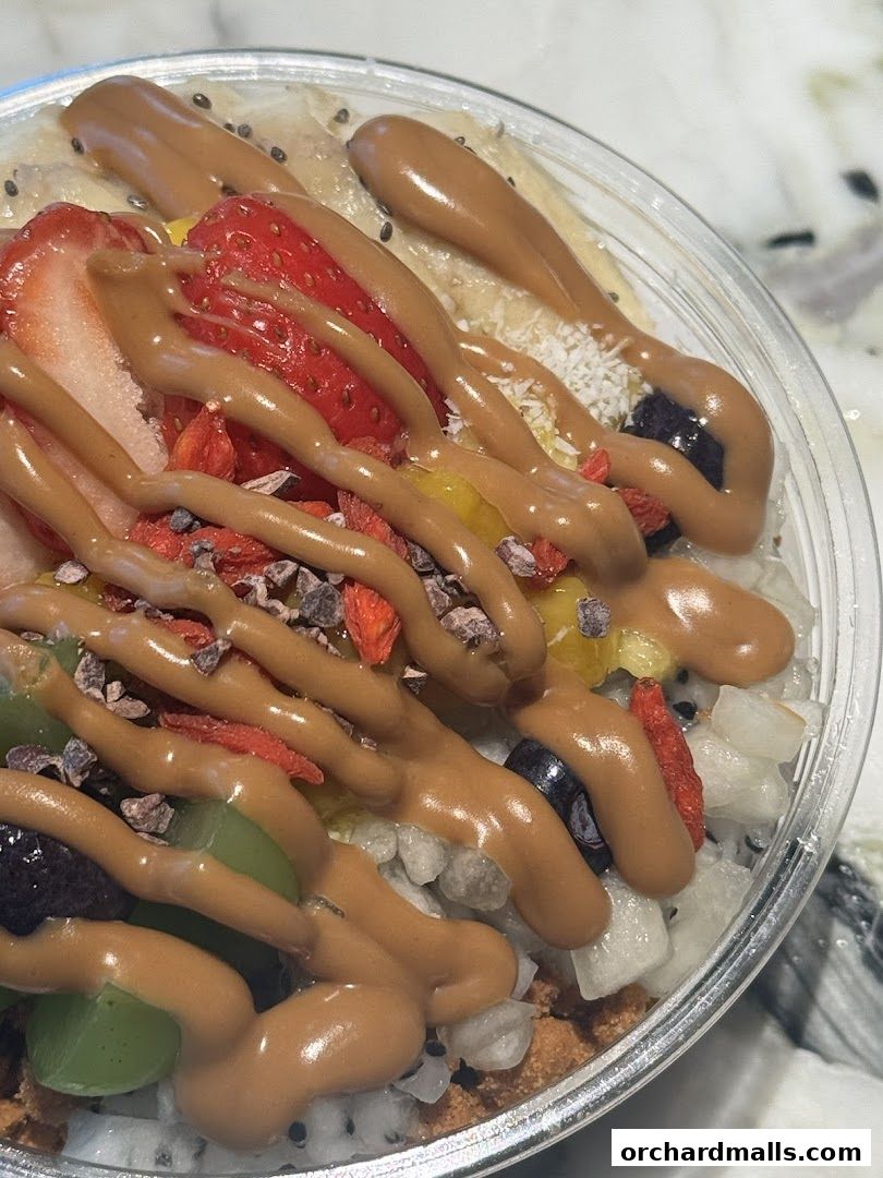 A close-up of a delicious acai bowl topped with fruits and a drizzle of peanut butter.