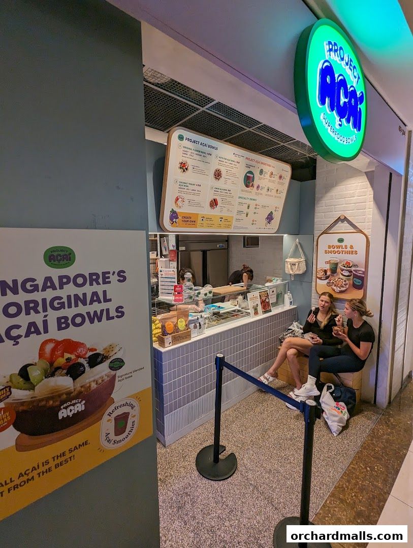 Project Acai Ngee Ann City shop front with a menu and customers sitting nearby.