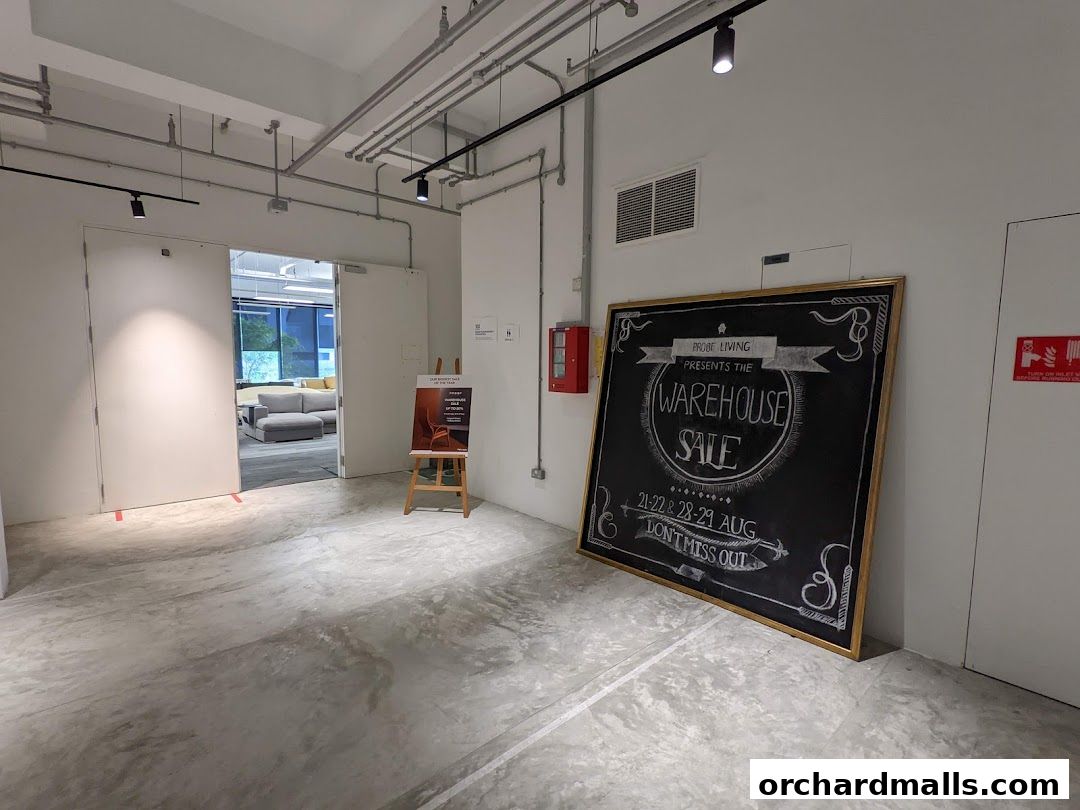 A shop interior with a large chalkboard announcing a warehouse sale and an open doorway revealing furniture.