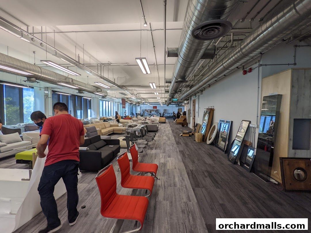A spacious showroom filled with various sofas, chairs, and mirrors, with staff arranging items.