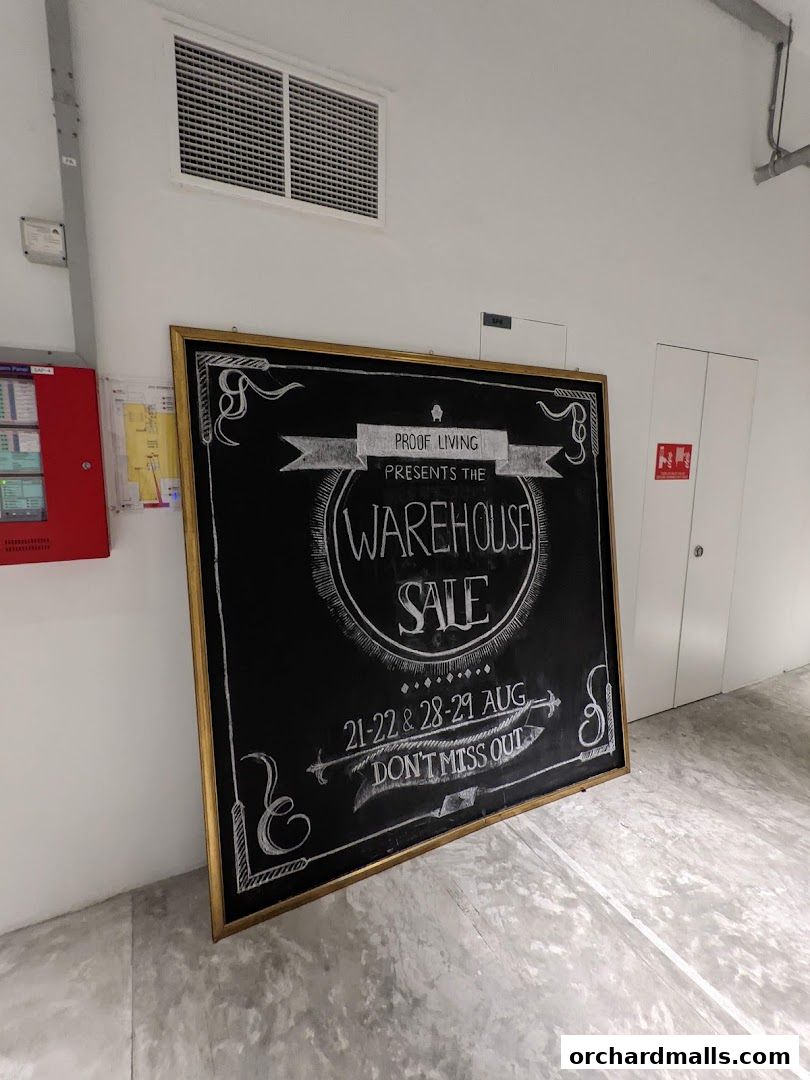 A chalkboard sign announces a warehouse sale for Proof Living on specific dates in August.