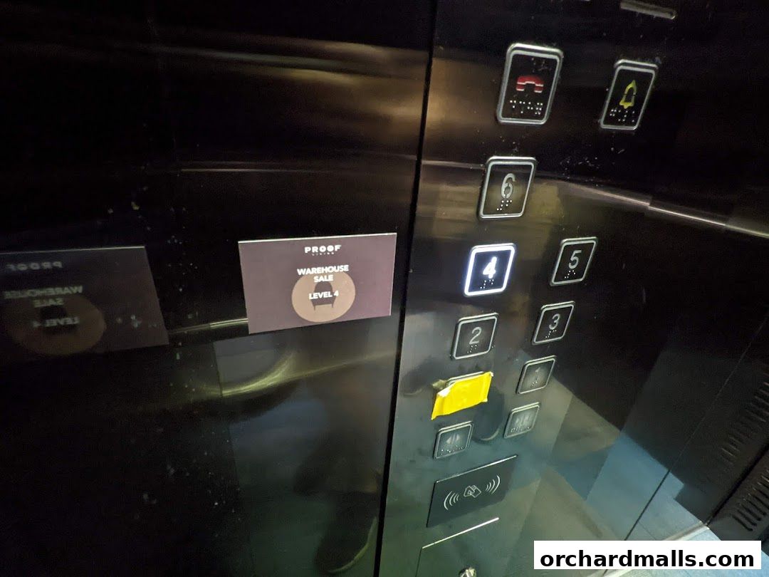 An elevator panel with a sign indicating a warehouse sale on Level 4.