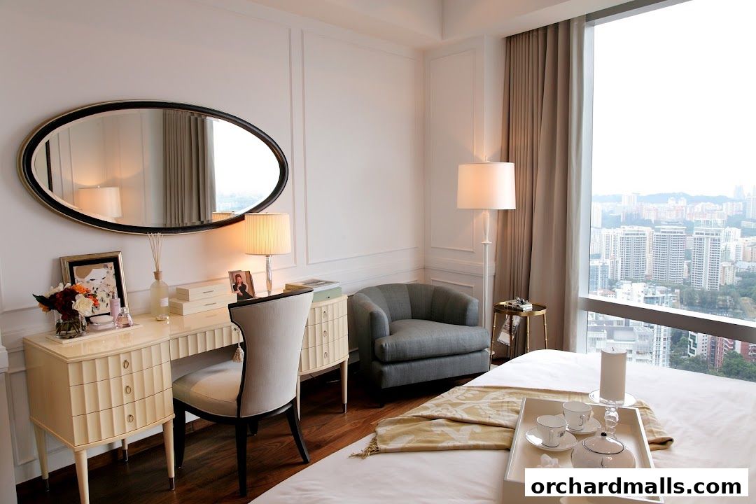 A luxurious hotel room with a vanity, chair, armchair, and a bed with a tea set.