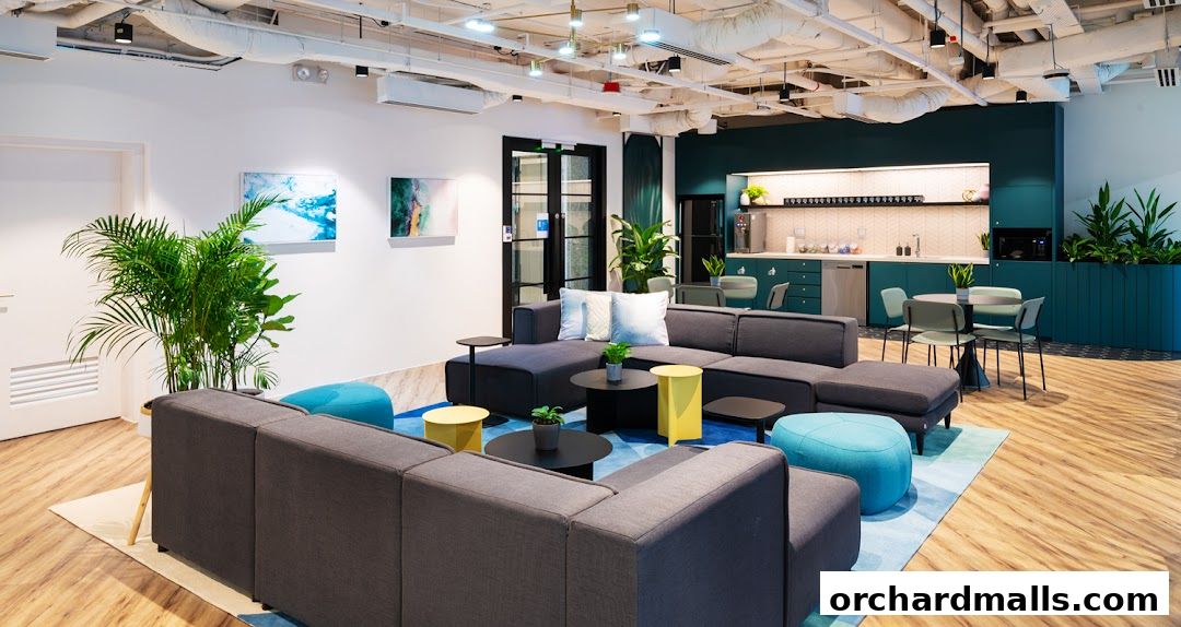 A modern lounge area with comfortable seating, plants, and a kitchenette.