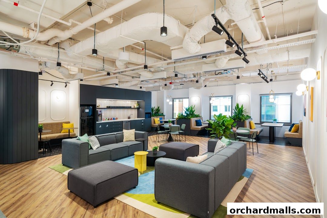 A modern and spacious lounge area with comfortable seating, plants, and a kitchenette.