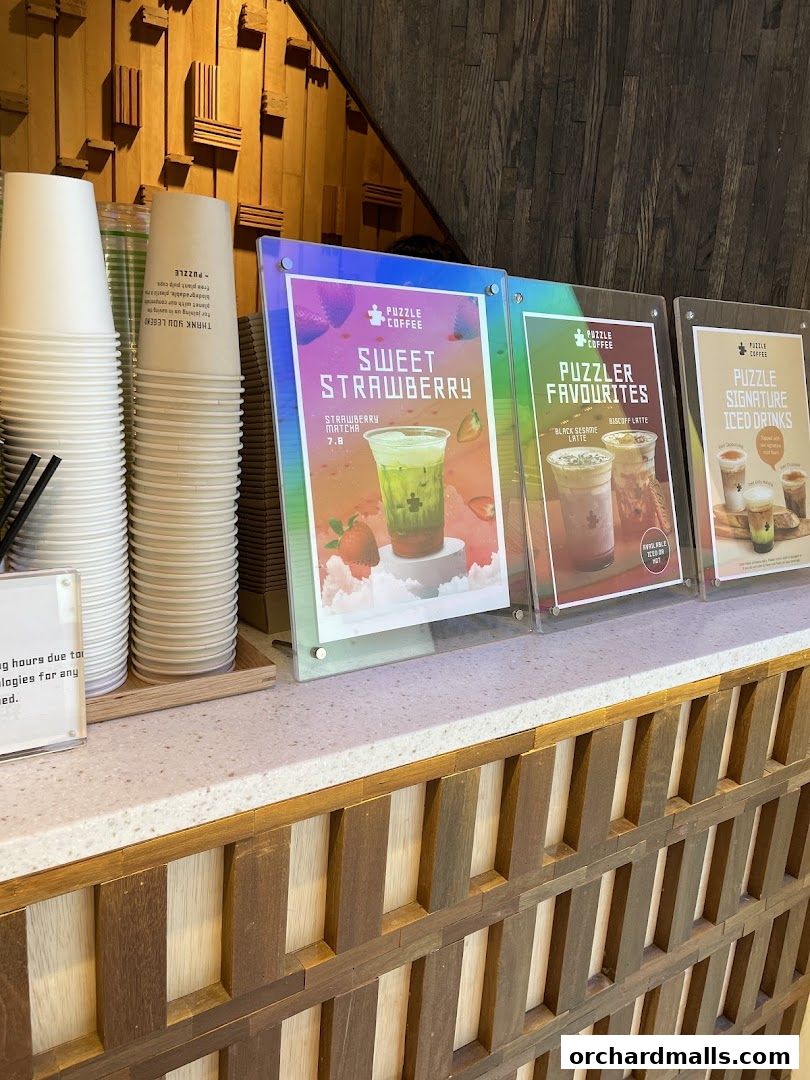 A counter display at Puzzle Coffee featuring colorful menu boards and stacks of cups.