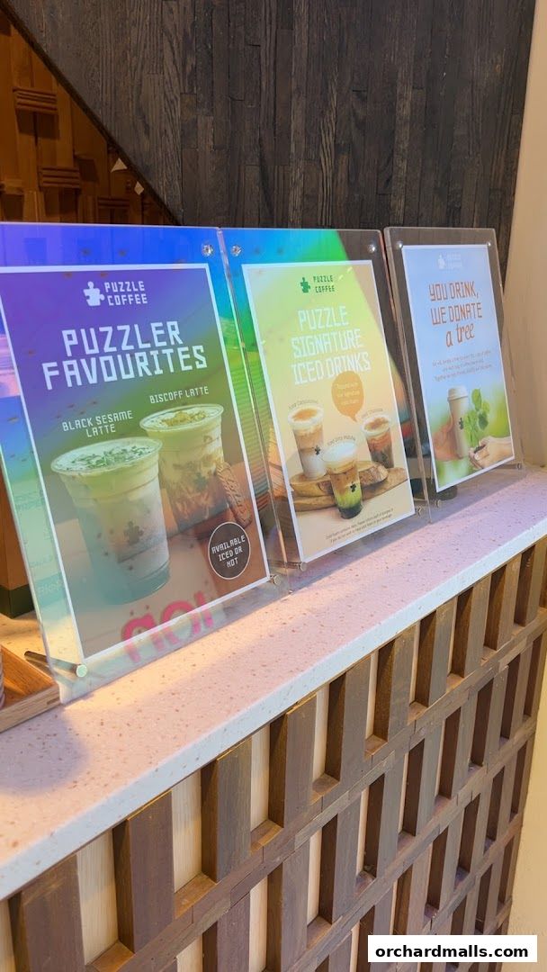 Three acrylic displays showcasing coffee drinks and a donation initiative.