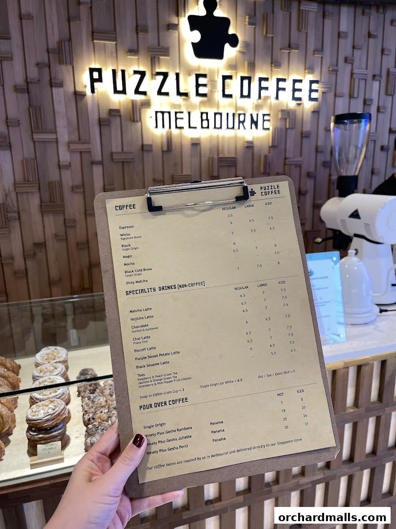 A person holds a menu for Puzzle Coffee Melbourne, showcasing coffee and specialty drinks.