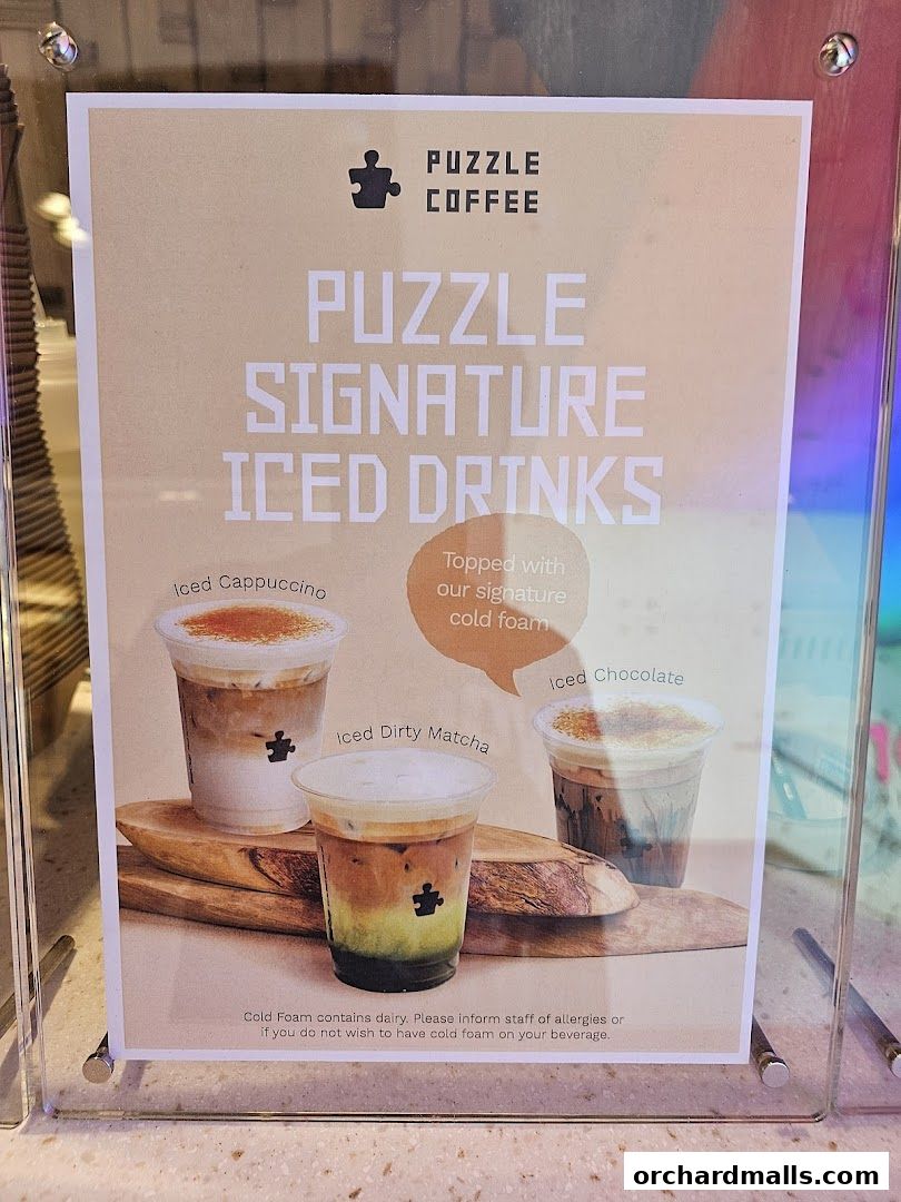 A sign displays Puzzle Coffee's signature iced drinks with cold foam.
