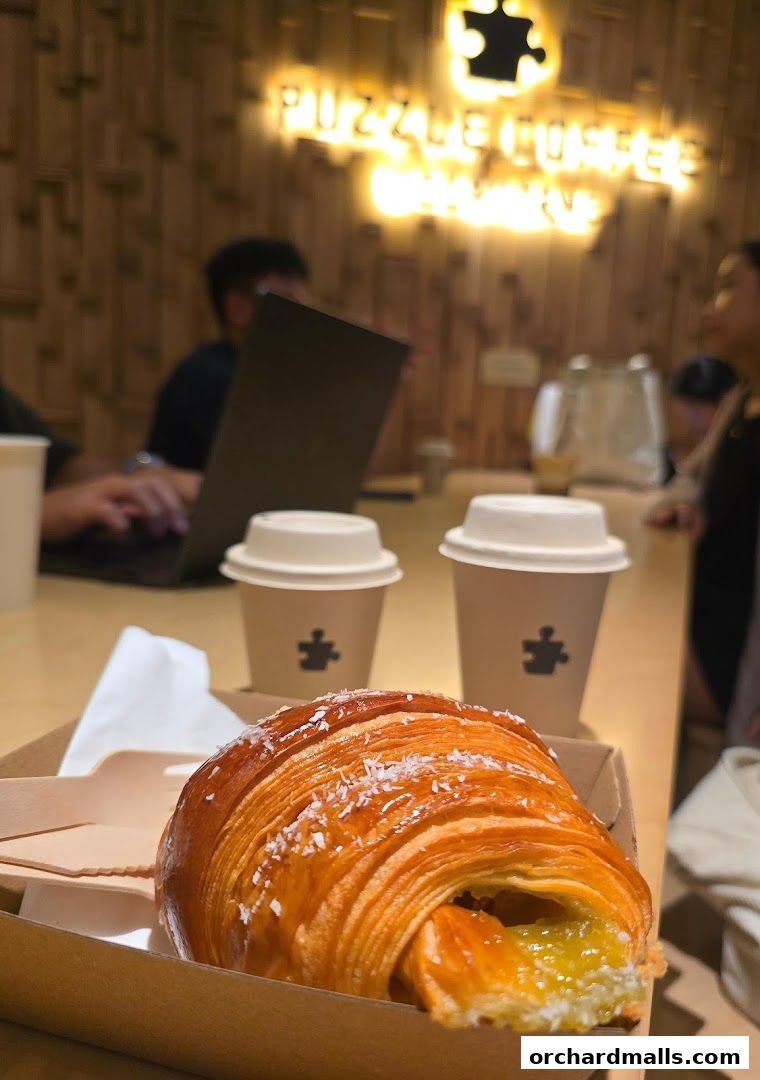 A croissant and two coffee cups on a table at Puzzle Coffee.