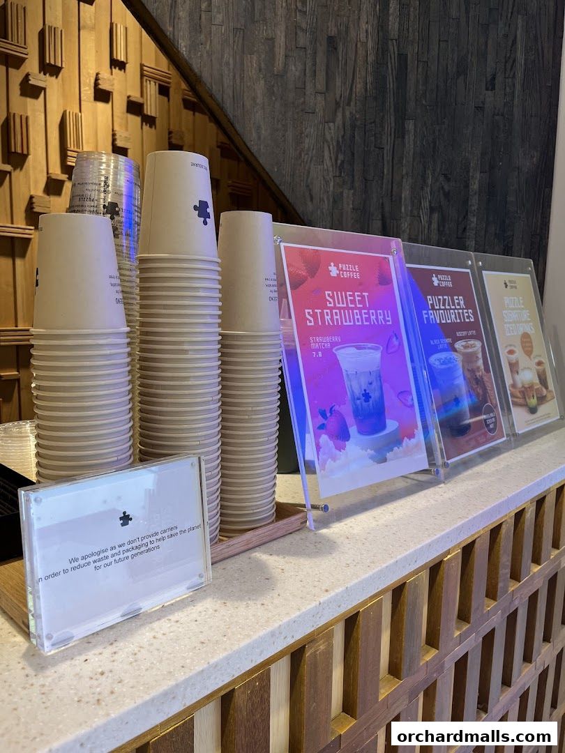 Stacks of coffee cups and promotional signs for drinks at Puzzle Coffee.