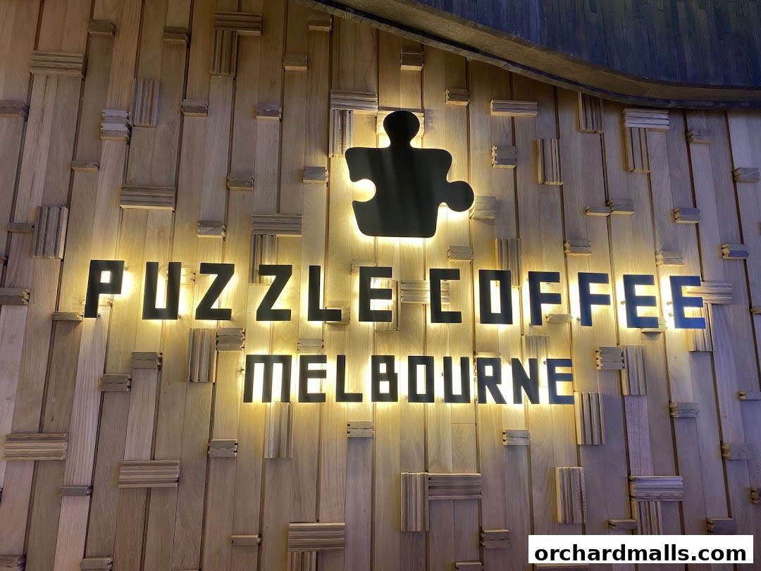 The Puzzle Coffee Melbourne sign is illuminated against a textured wooden wall.