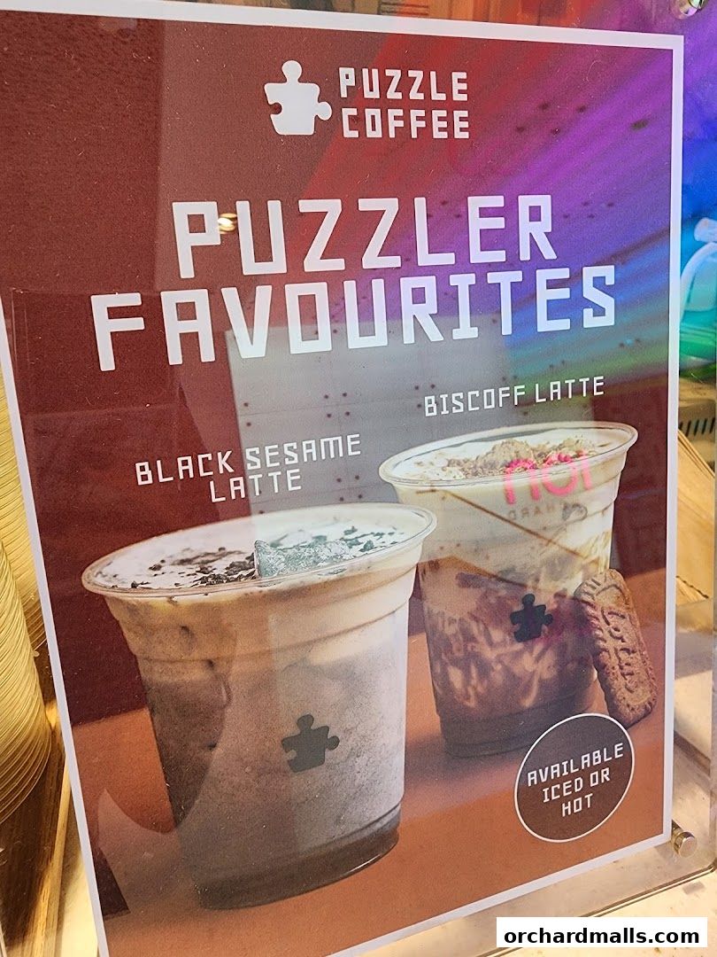 A sign showcasing two popular drinks from Puzzle Coffee: Black Sesame Latte and Biscoff Latte.