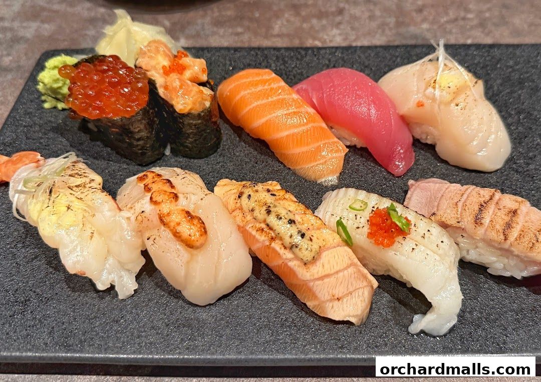 A platter of assorted sushi, including salmon, tuna, scallop, and shrimp, with wasabi and ginger.