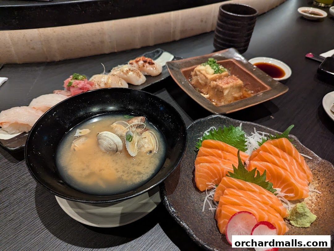 A table laden with various Japanese dishes, including sashimi, miso soup, and fried tofu.