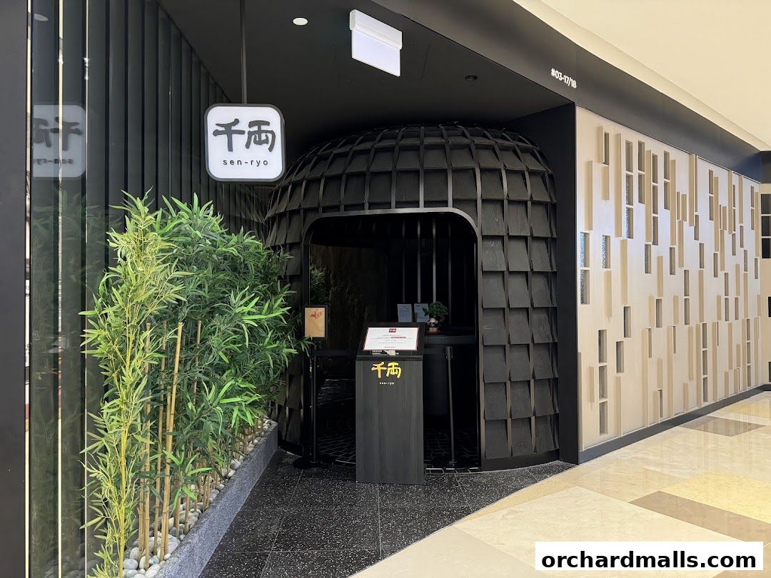 The entrance of Sen-Ryo, a Japanese restaurant, with a distinctive black, textured facade and bamboo plants.