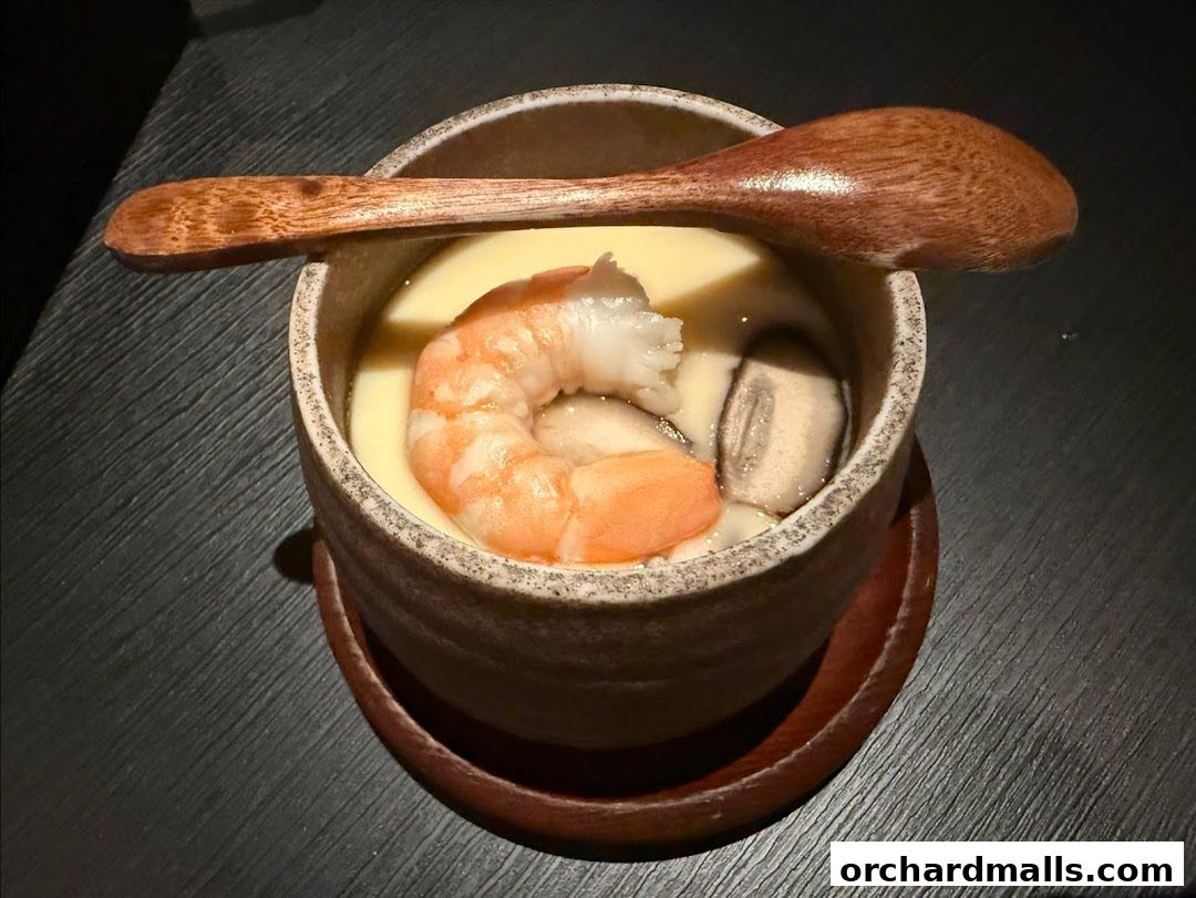 A close-up of a Japanese steamed egg custard with shrimp and mushrooms.