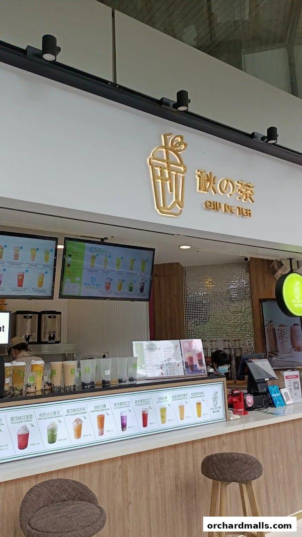 A modern bubble tea shop counter with digital menus and a variety of drinks displayed.