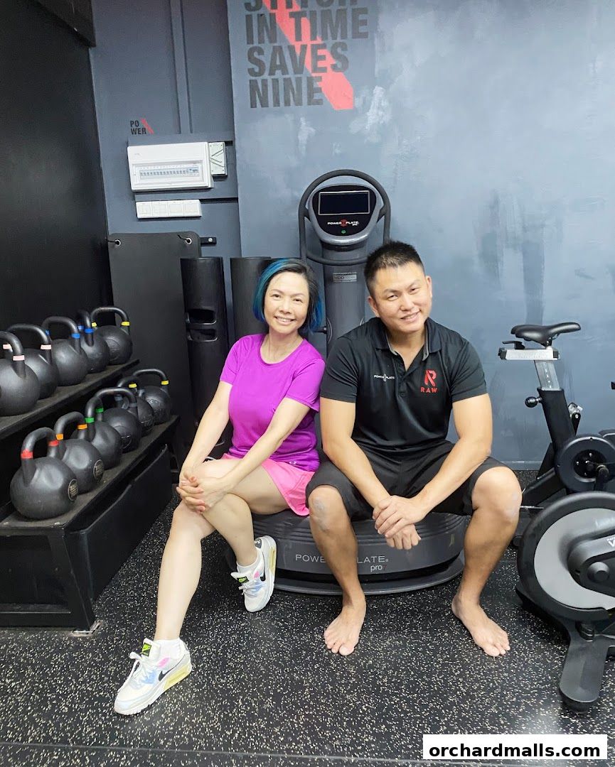 Two people posing in a gym with kettlebells and exercise equipment.