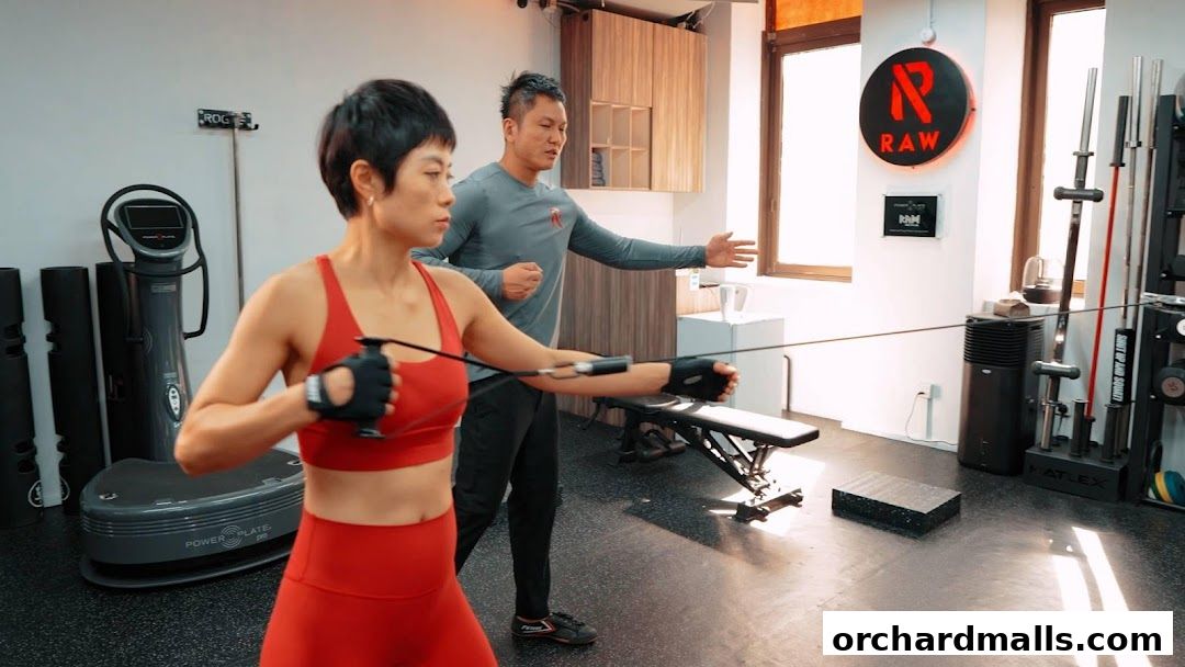 A personal trainer guides a woman performing a cable exercise in a gym.