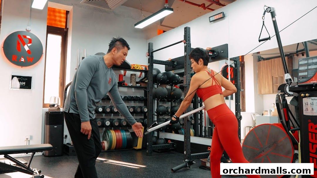 A personal trainer guides a client through a cable machine exercise in a gym.