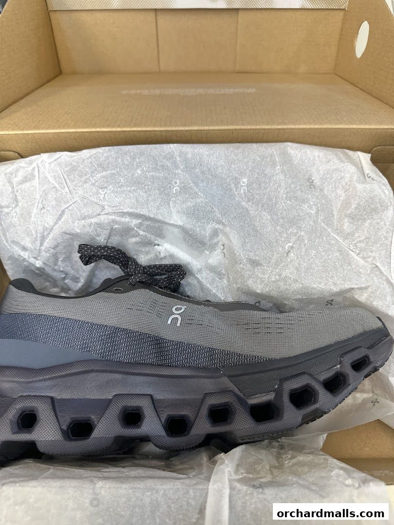 A grey running shoe with a distinctive sole, presented in its original packaging.