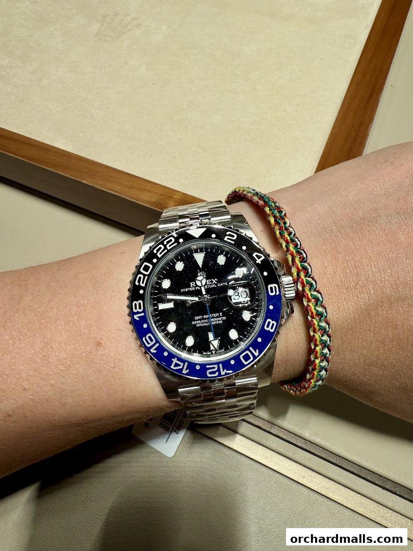A close-up of a Rolex GMT-Master II watch on a wrist with a colorful bracelet.