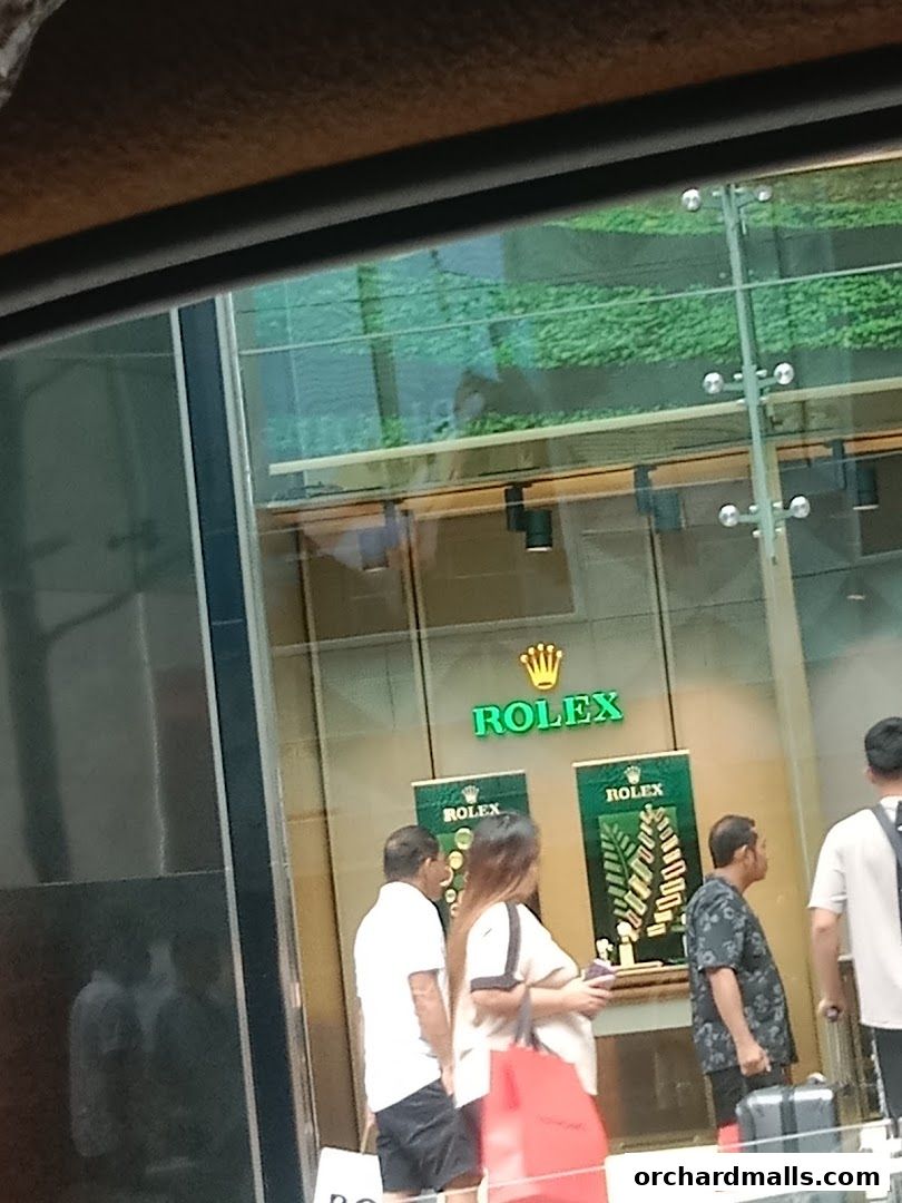 People looking at watches displayed in a Rolex boutique window.