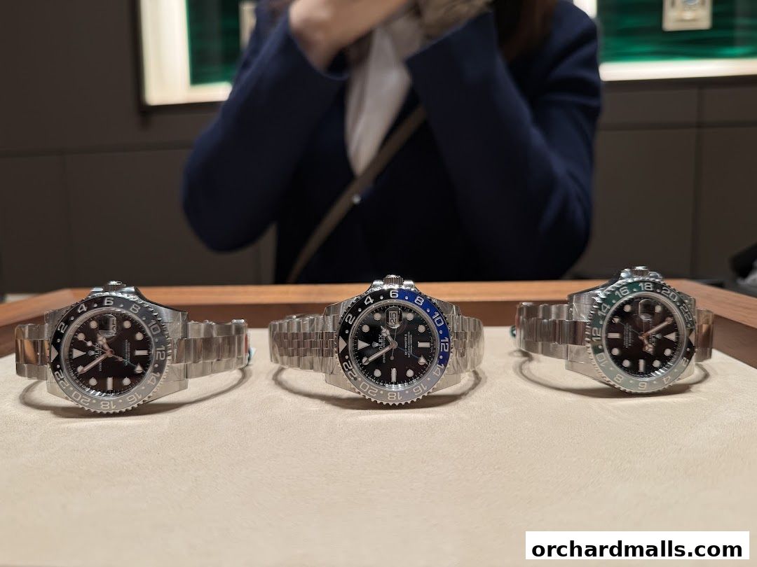 Three Rolex watches with metal bands are displayed on a light-colored surface.