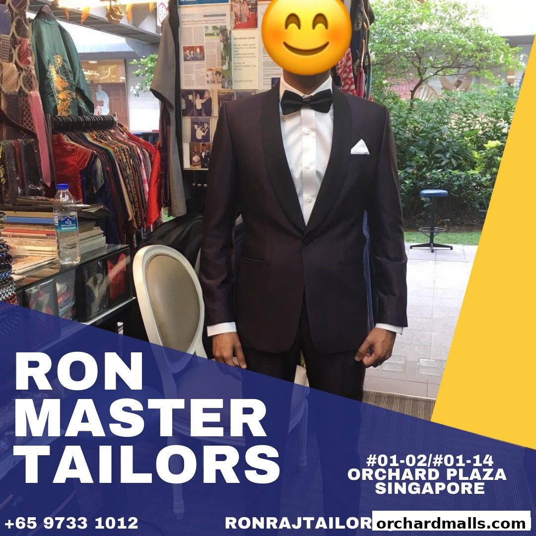A tailor shop displays a man in a tuxedo with various suits and fabrics in the background.