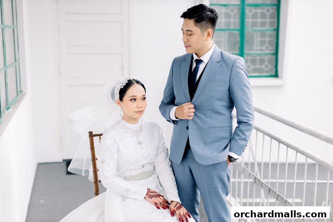 A bride in a white gown and groom in a blue suit pose for a portrait.