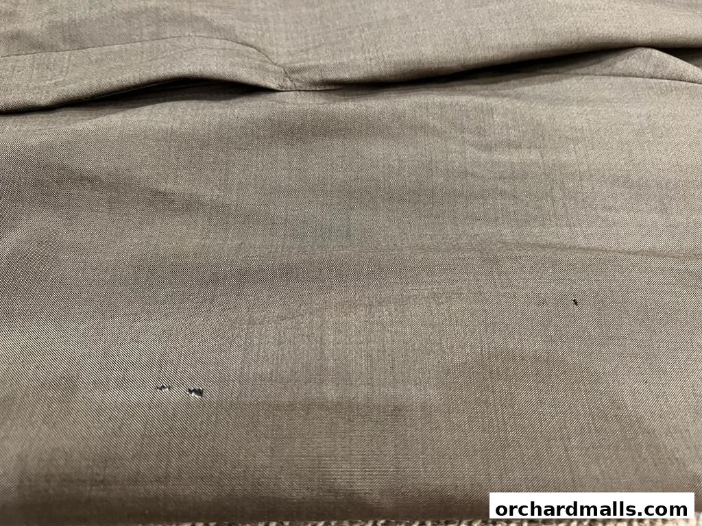 Close-up of a grey fabric with subtle texture and a small dark mark.