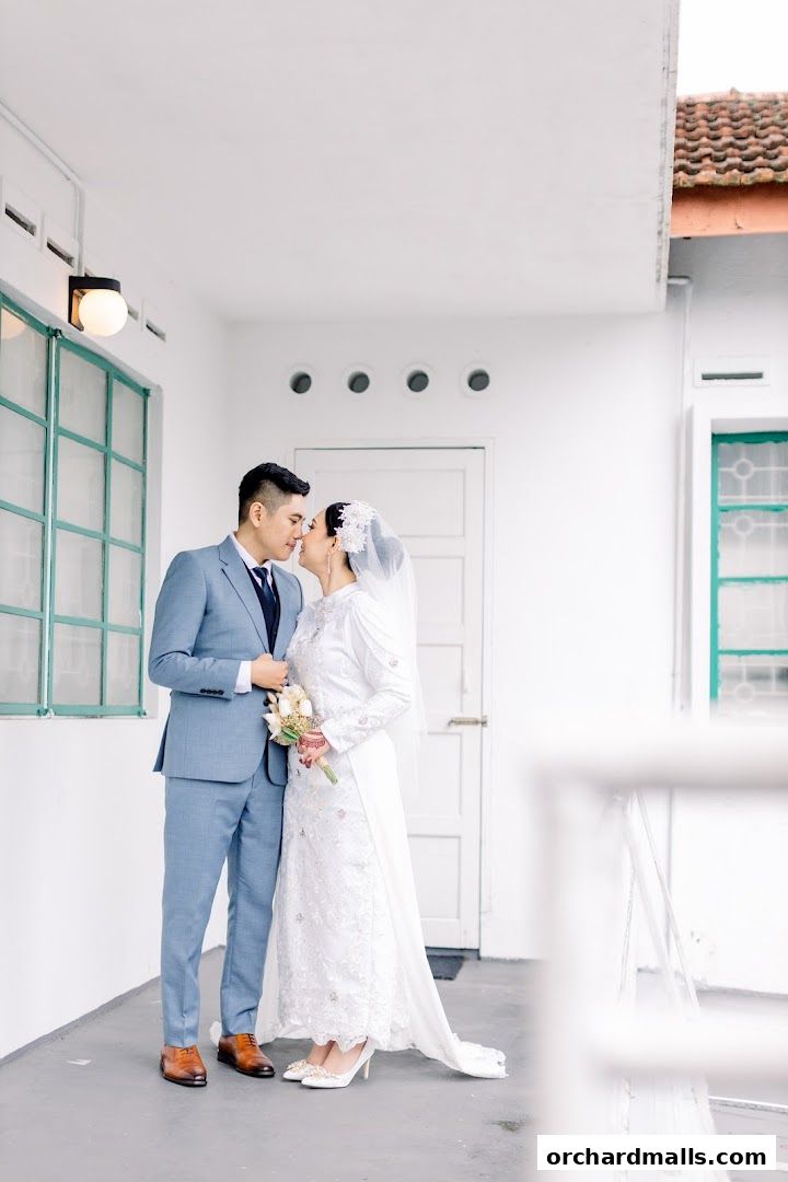 A bride and groom in wedding attire share a tender moment on a balcony.