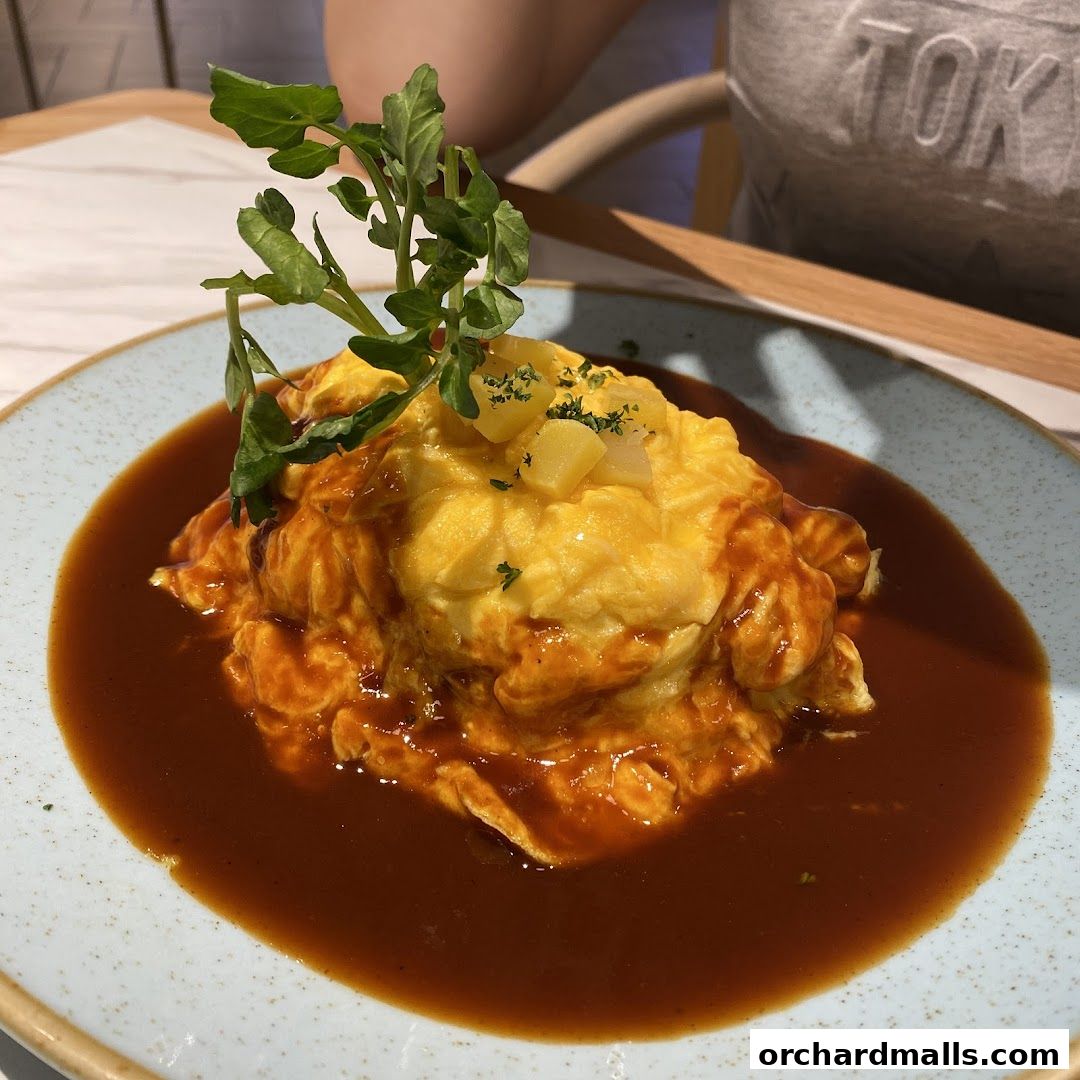 A delicious omurice dish with a rich brown sauce and fresh greens.
