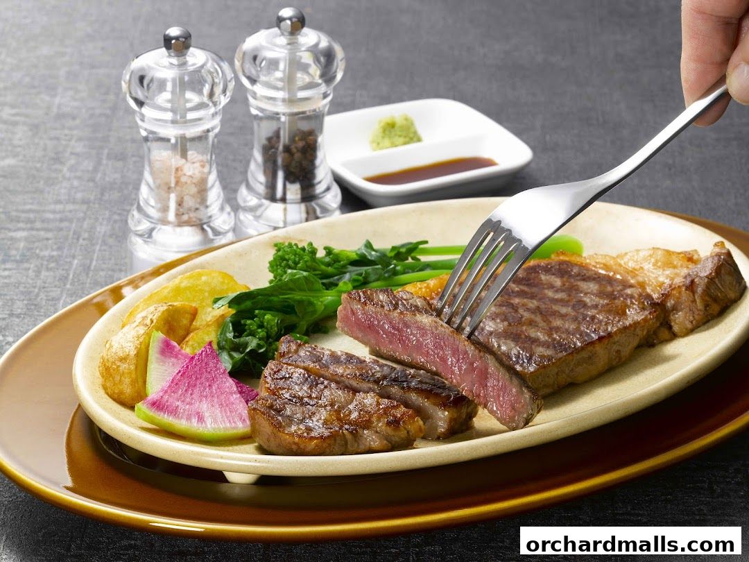 A fork is cutting into a juicy steak served with vegetables and potatoes.