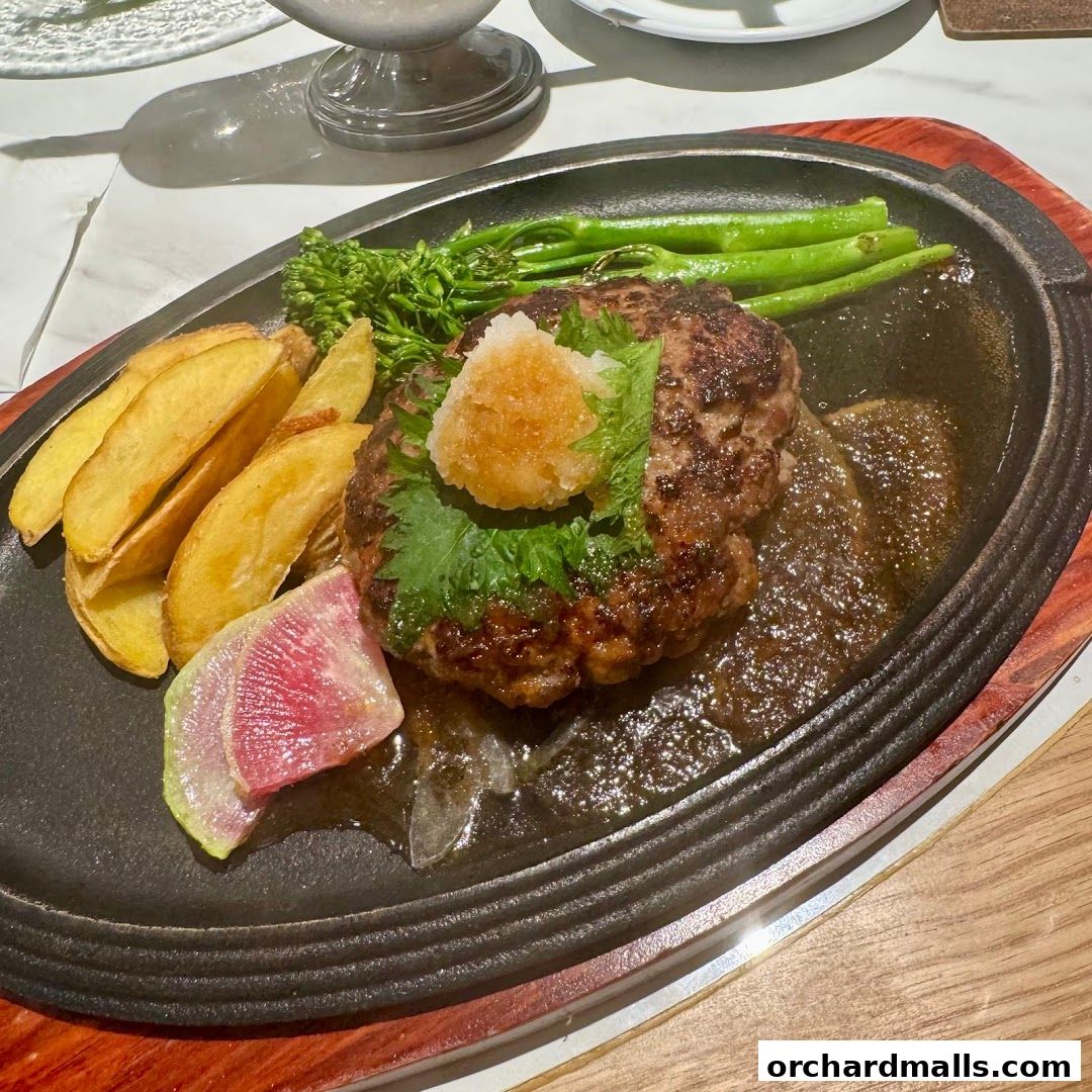 A sizzling hamburger steak served with potato wedges, broccoli, and a radish slice.