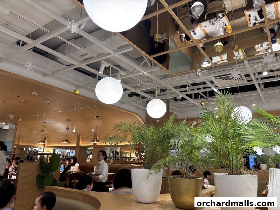 Interior view of a restaurant with modern decor, plants, and hanging lights.