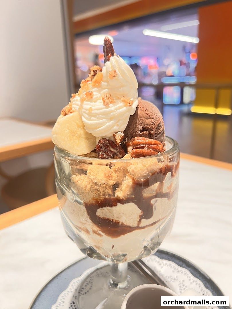 A delicious ice cream sundae with whipped cream, chocolate ice cream, bananas, nuts, and chocolate sauce.