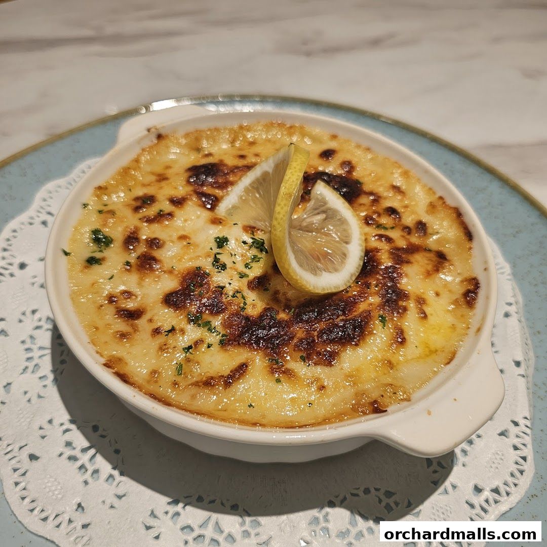 A close-up of a baked dish with melted cheese and lemon slices.