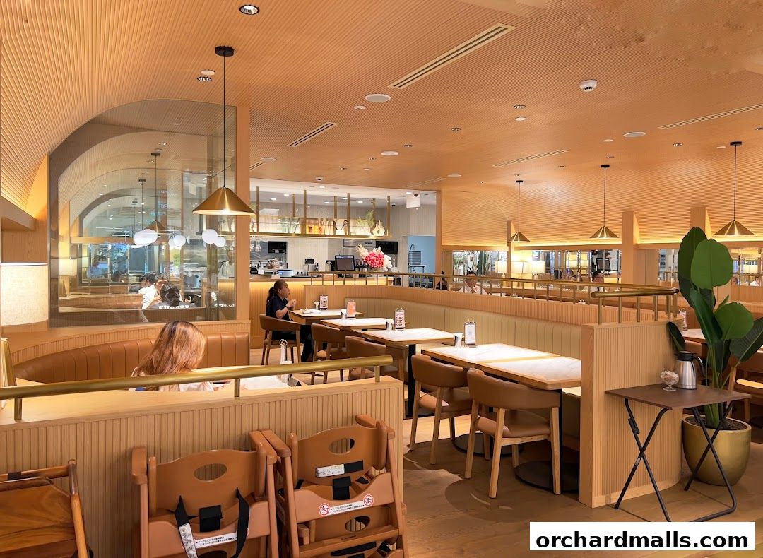 Interior of a modern restaurant with wooden accents, booth seating, and tables.