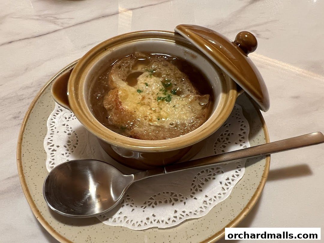 A close-up of a steaming bowl of French onion soup with melted cheese.