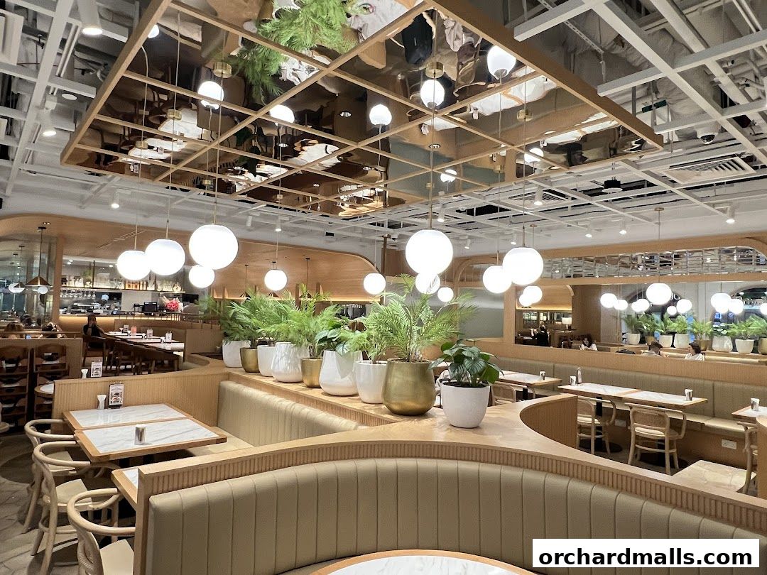 Interior view of a modern restaurant with booth seating, tables, and hanging lights.