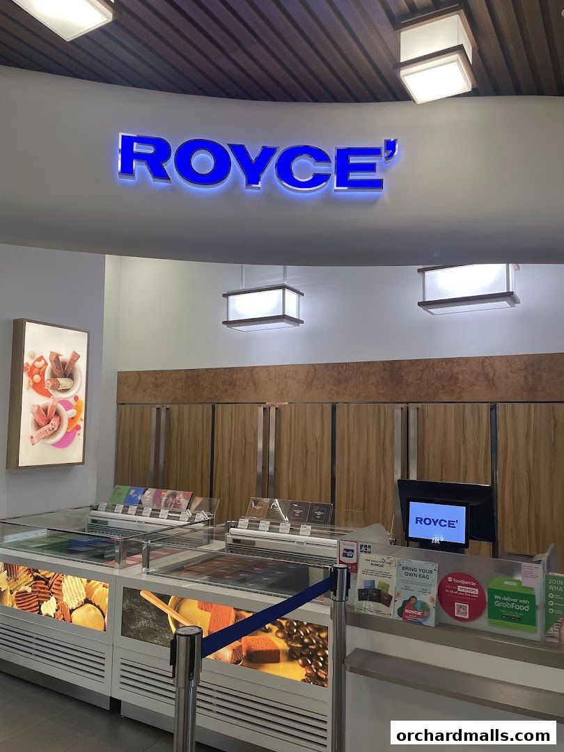 The Royce' shop front features a bright blue illuminated sign and display cases filled with chocolates and snacks.
