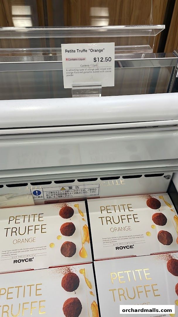 Boxes of Royce Petite Truffe Orange chocolates displayed in a refrigerated case.